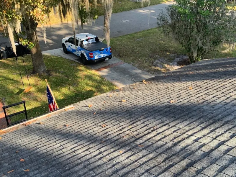 Bigfoot Roofing branded truck parked in a driveway with an American flag, seen from the roof