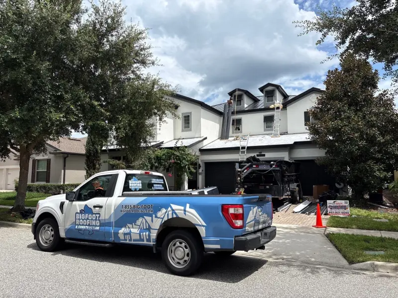 Bigfoot Roofing truck and trailer staged for an active standing seam metal roof replacement on a two-story townhome — Orlando, FL