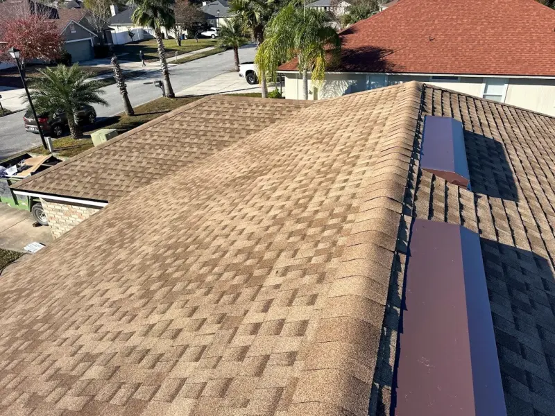 Drone view of a finished tan architectural shingle roof in a Central Florida neighborhood with palm trees