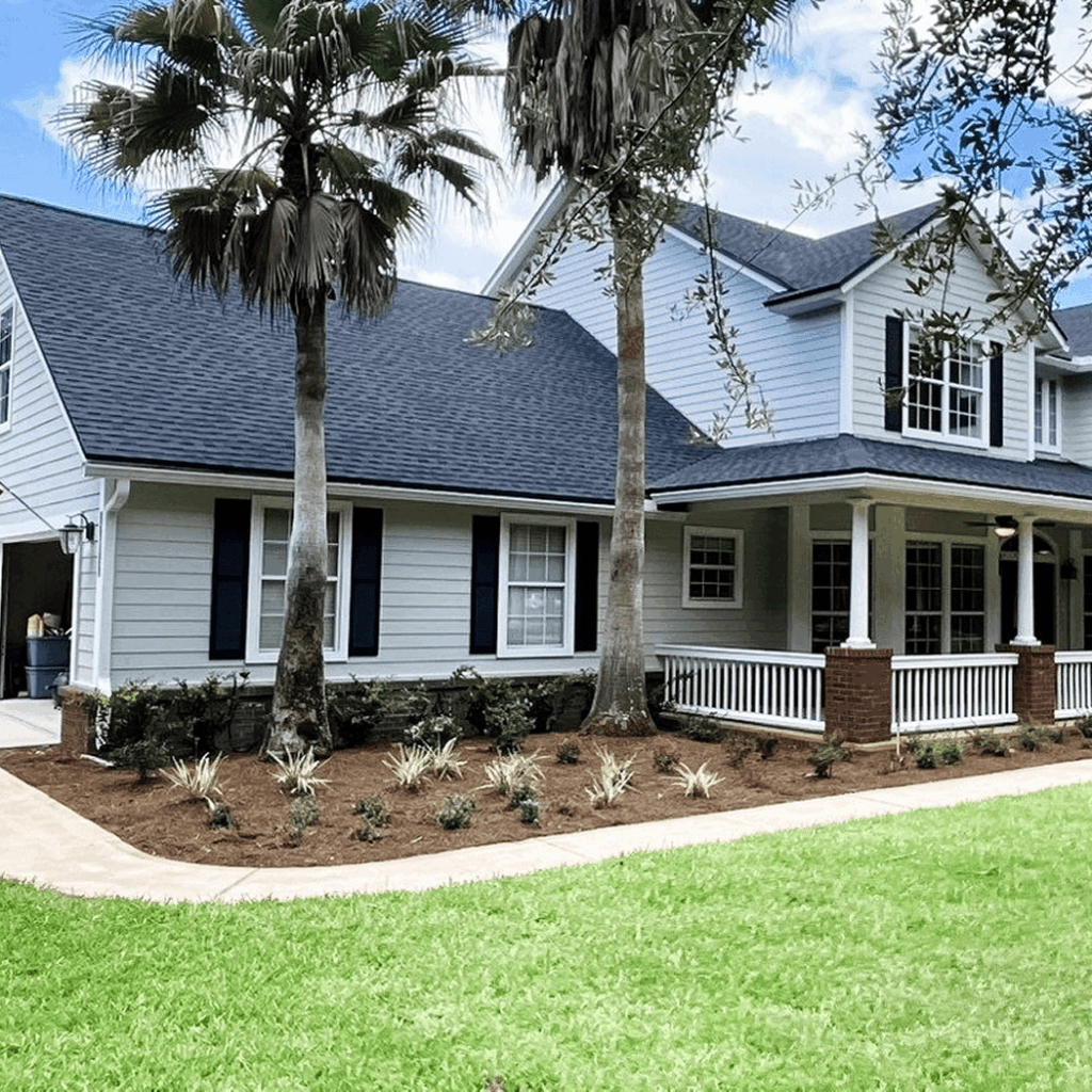 Exterior of a completed home with new roofing and siding surrounded by palm trees and a grass lawn.