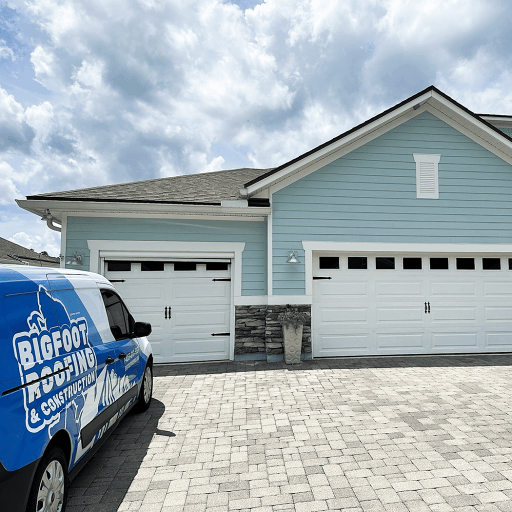 Bigfoot Roofing and Construction work truck parked outside of a residential driveway and home.