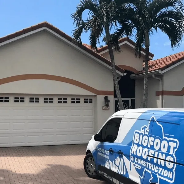 Bigfoot Roofing and Construction work truck parked outside of a residential driveway and home.